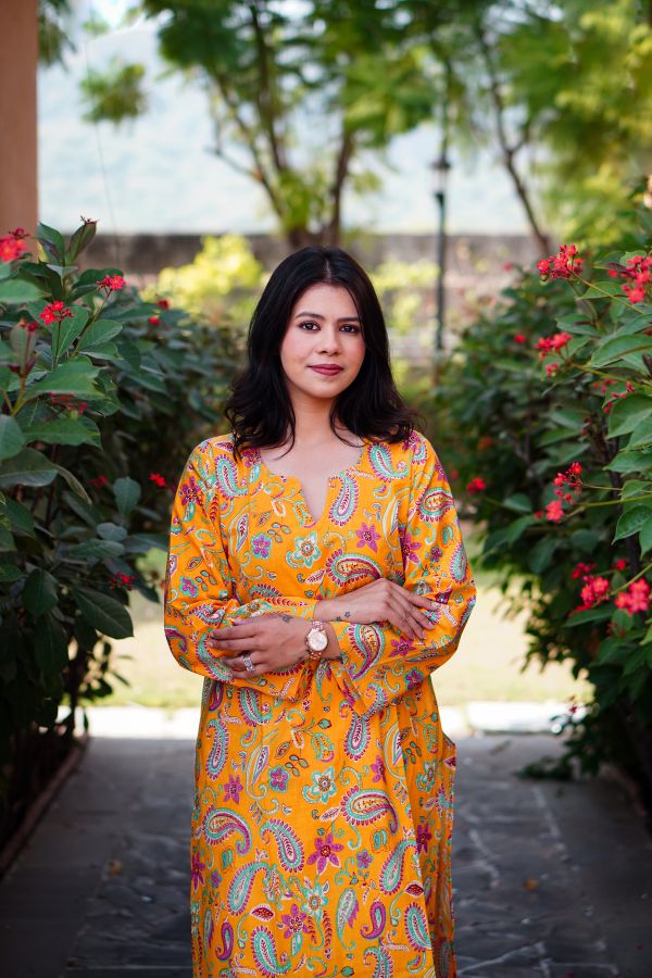 Front portrait of a woman wearing the Printed Pure Cotton Mustard Kurta Set with bright paisley motifs.